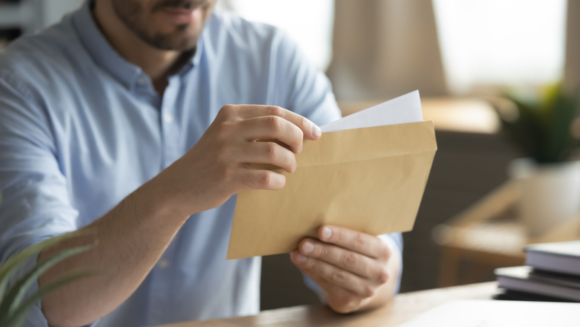 Ein Mann im Büro legt ein Schreiben in einen Briefumschlag.
