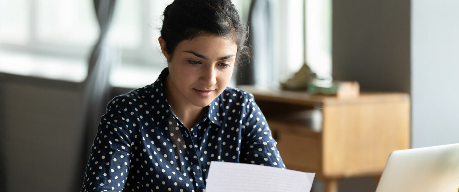 Eine junge Frau liest ein Dokument an ihrem Schreibtisch