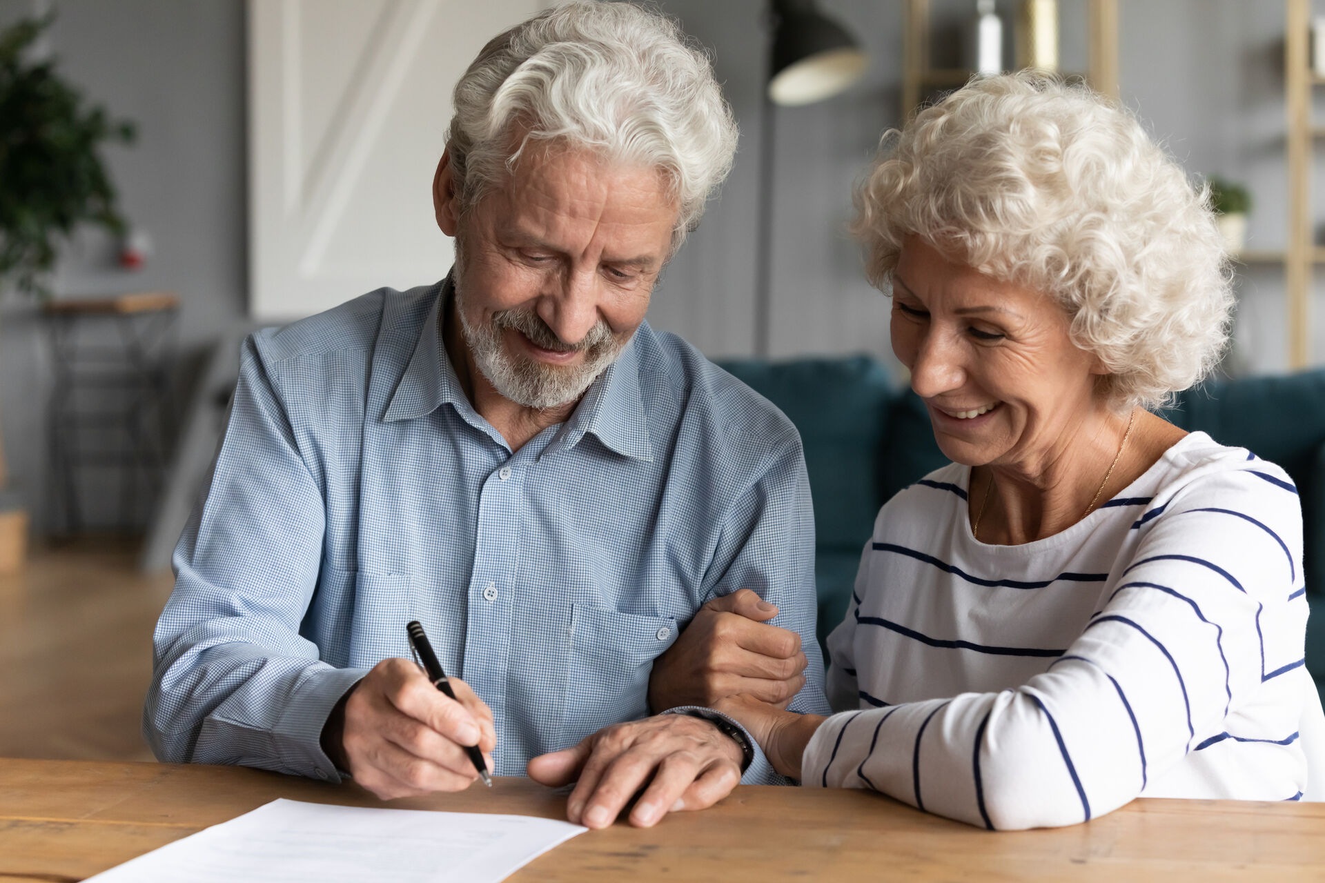Ein älteres Ehepaar unterschreibt ein Dokument